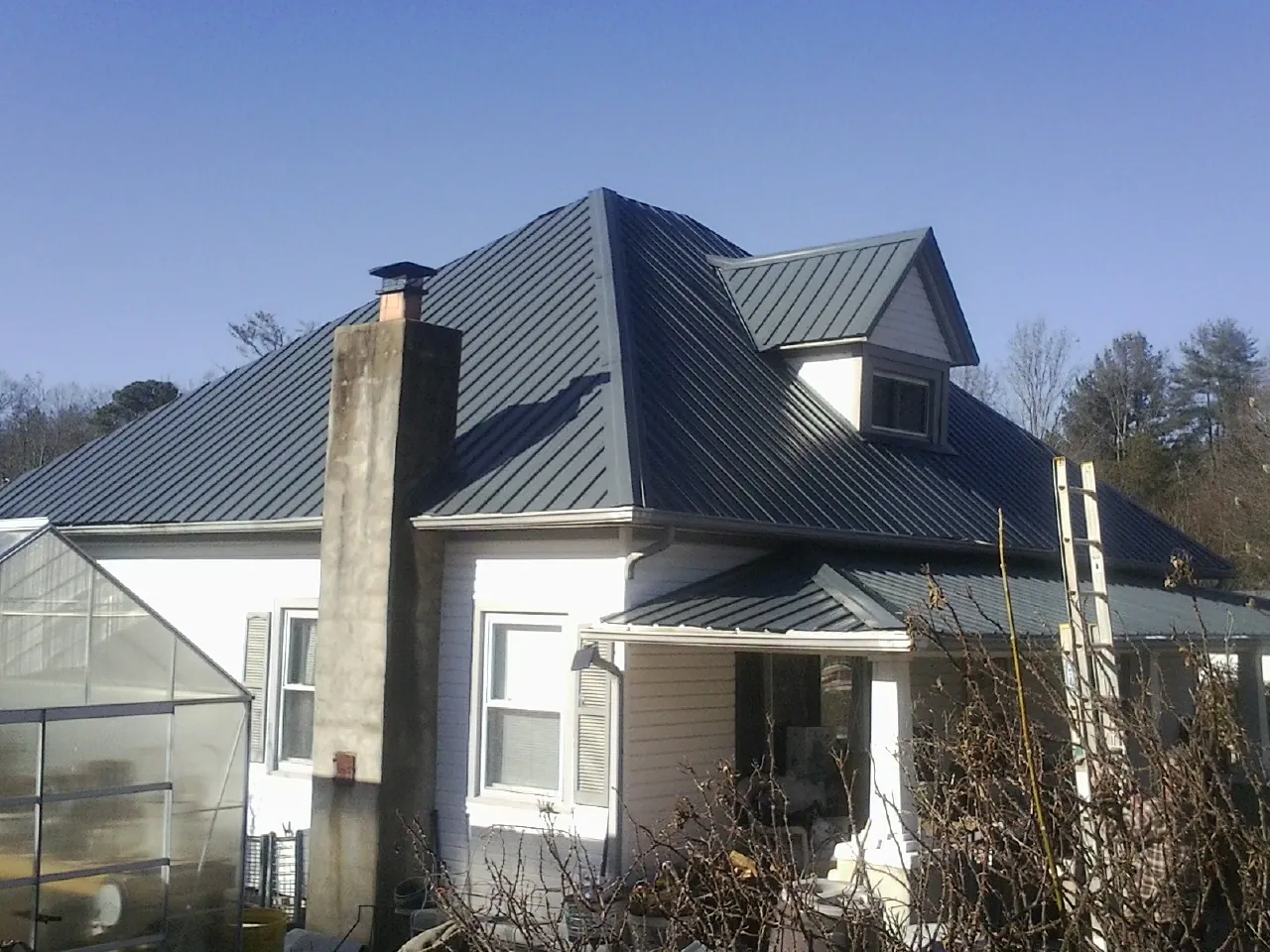 Dark blue standing seam metal roof on a white farmhouse with dormer — Slate & Tile Roof Repair by Roofing Brothers in Zieglerville