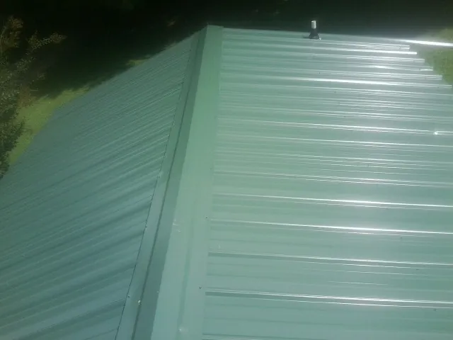 New green metal panels meeting at the ridge of a roof — Flat Roof Repair work by our crew in Zieglerville