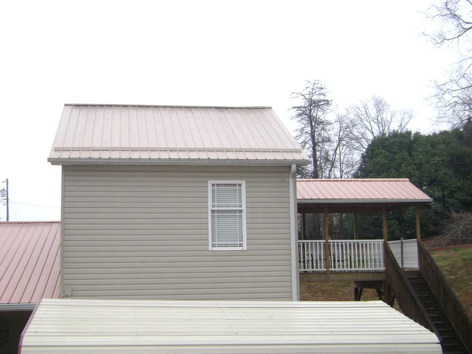 Tan metal roofs on a two story addition and attached porch, from a Roof Replacement job in Zieglerville