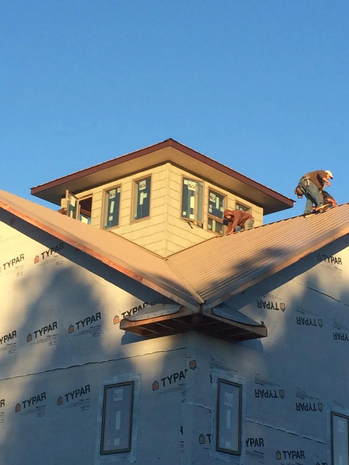 Roofers working around a rooftop cupola on a new metal roof at sunset — Roof Waterproofing in Zieglerville by Roofing Brothers